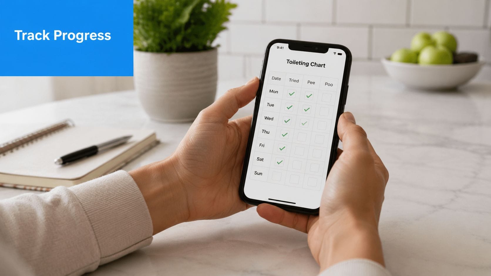 A person holds a smartphone showing a digital toileting progress chart to track potty training success.