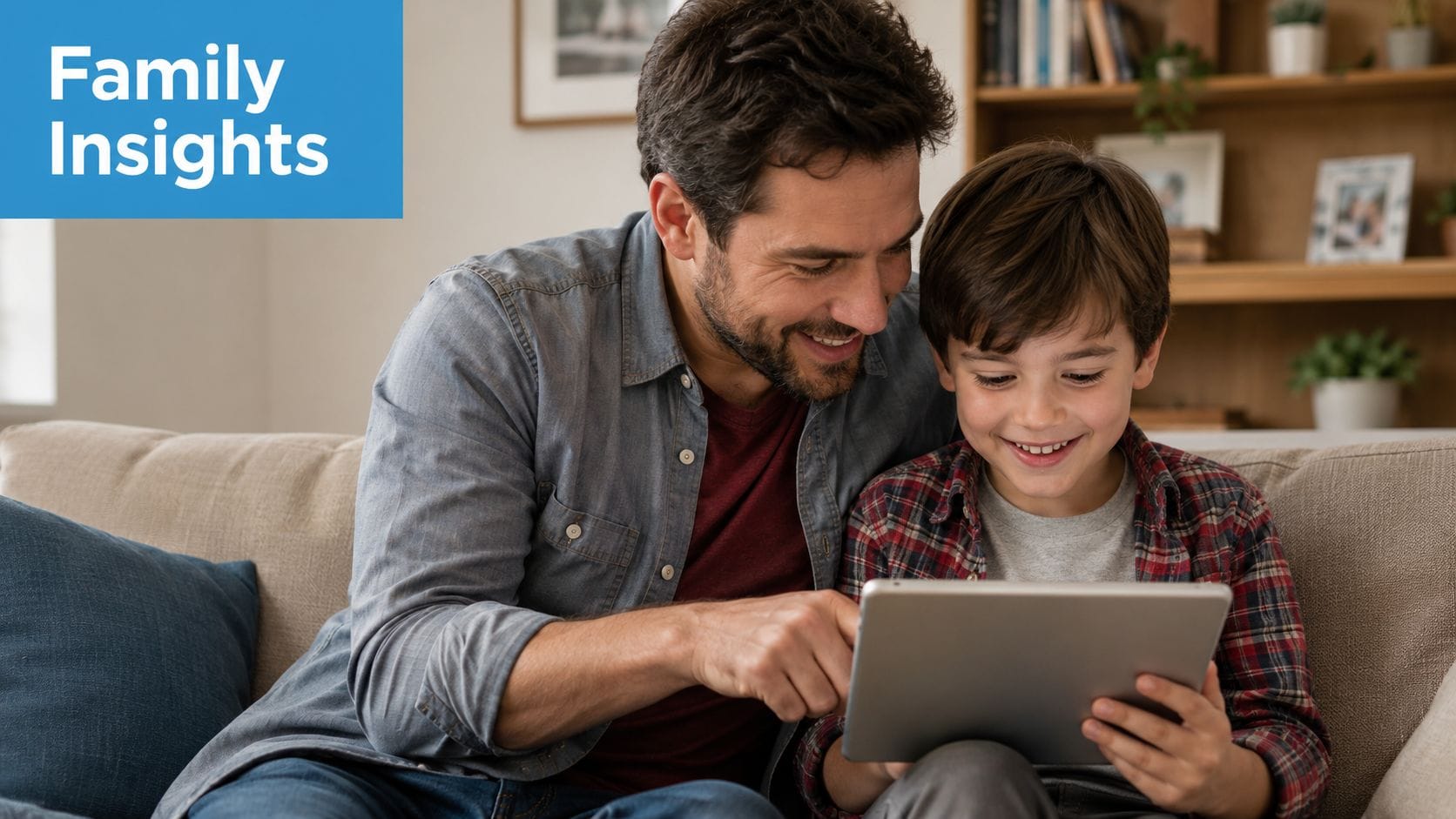 A smiling father and his young son sitting on a sofa while looking at a digital tablet together.