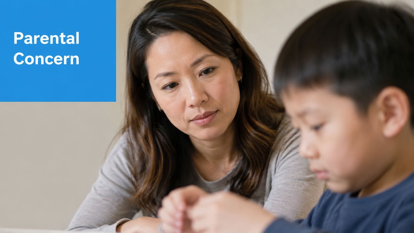 A concerned mother watching her young son as he exhibits repetitive finger movements during an interaction.