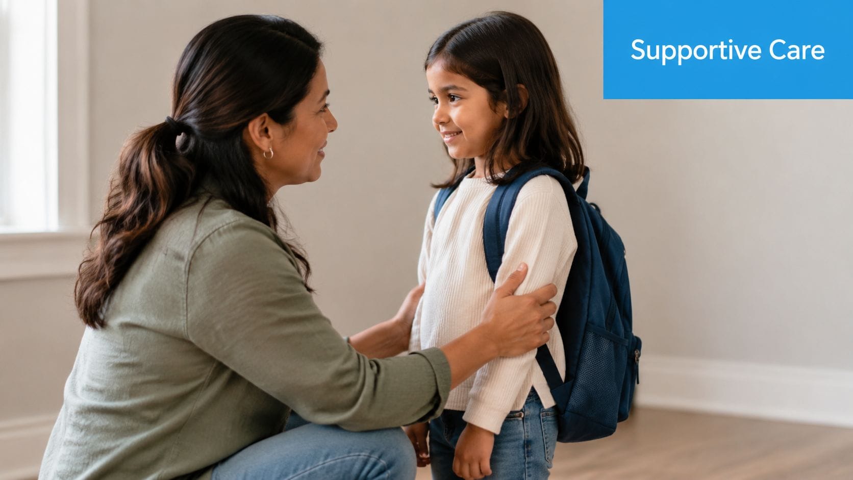 A caring mother kneels to encourage her young daughter who is wearing a school backpack.
