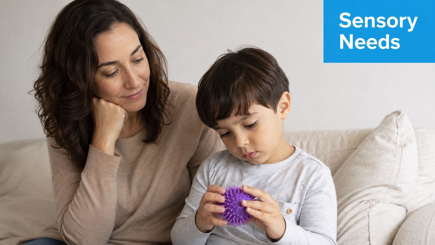 A woman looks on kindly as a young boy plays with a purple spiky sensory ball.