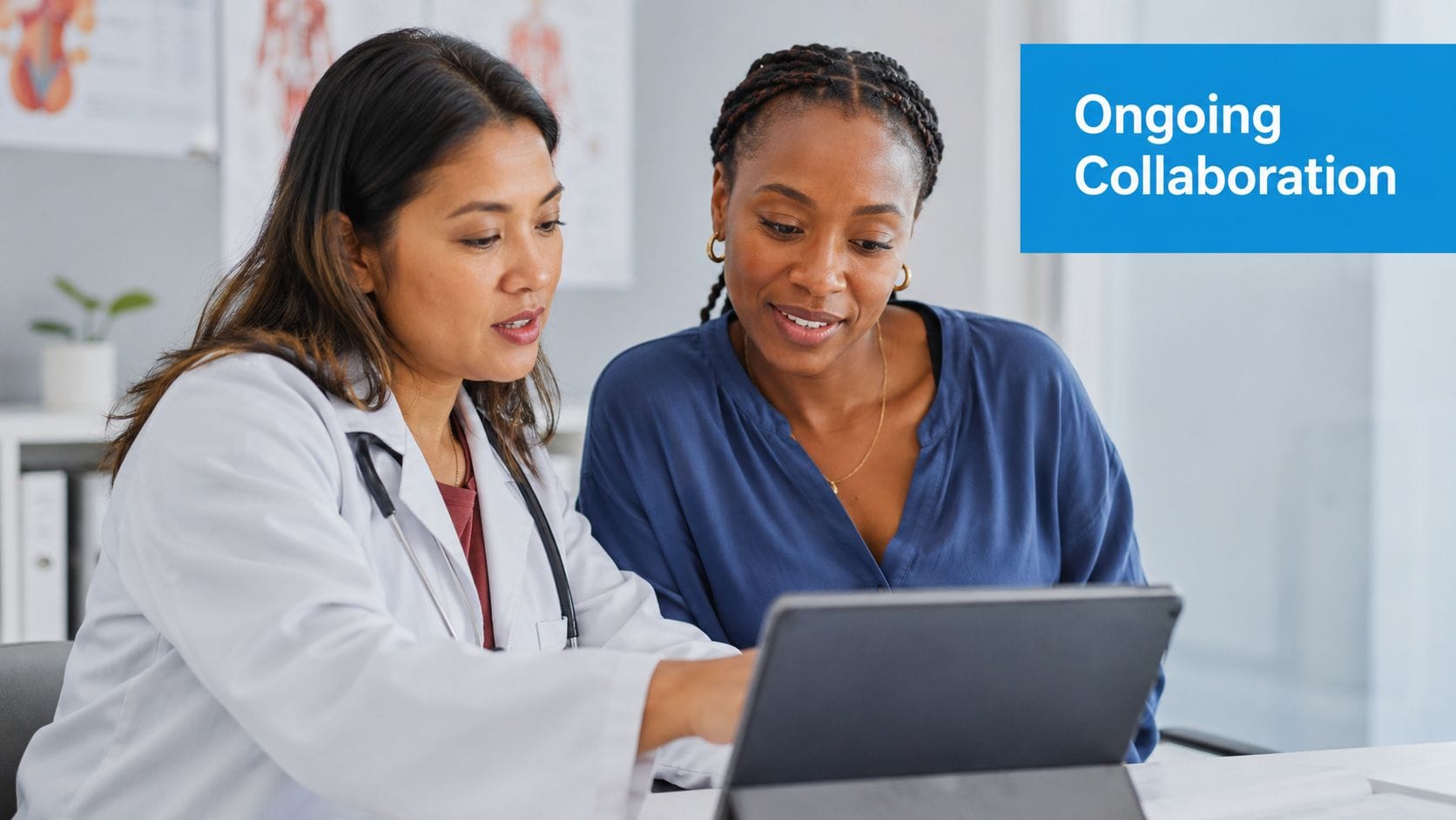 A female doctor in a white coat explains health information on a tablet to a female patient.